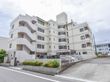 陽当たりの良い道路に面した4階建ての建物。周りはコンクリートできれいに整備され、駐車場も敷地内にある。