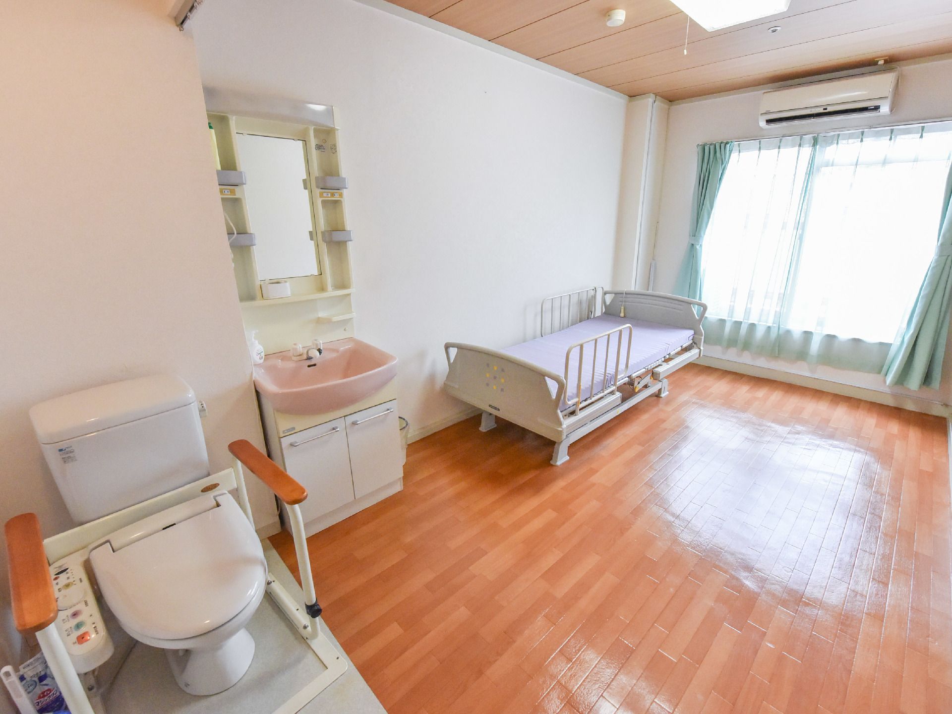 フローリングの床と木目調の天井、白い壁で落ち着いた雰囲気になっている。大きな窓から光が入り明るい部屋になっている。