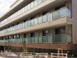 ベランダの壁に全面アクリル板を使用した4階建ての建物