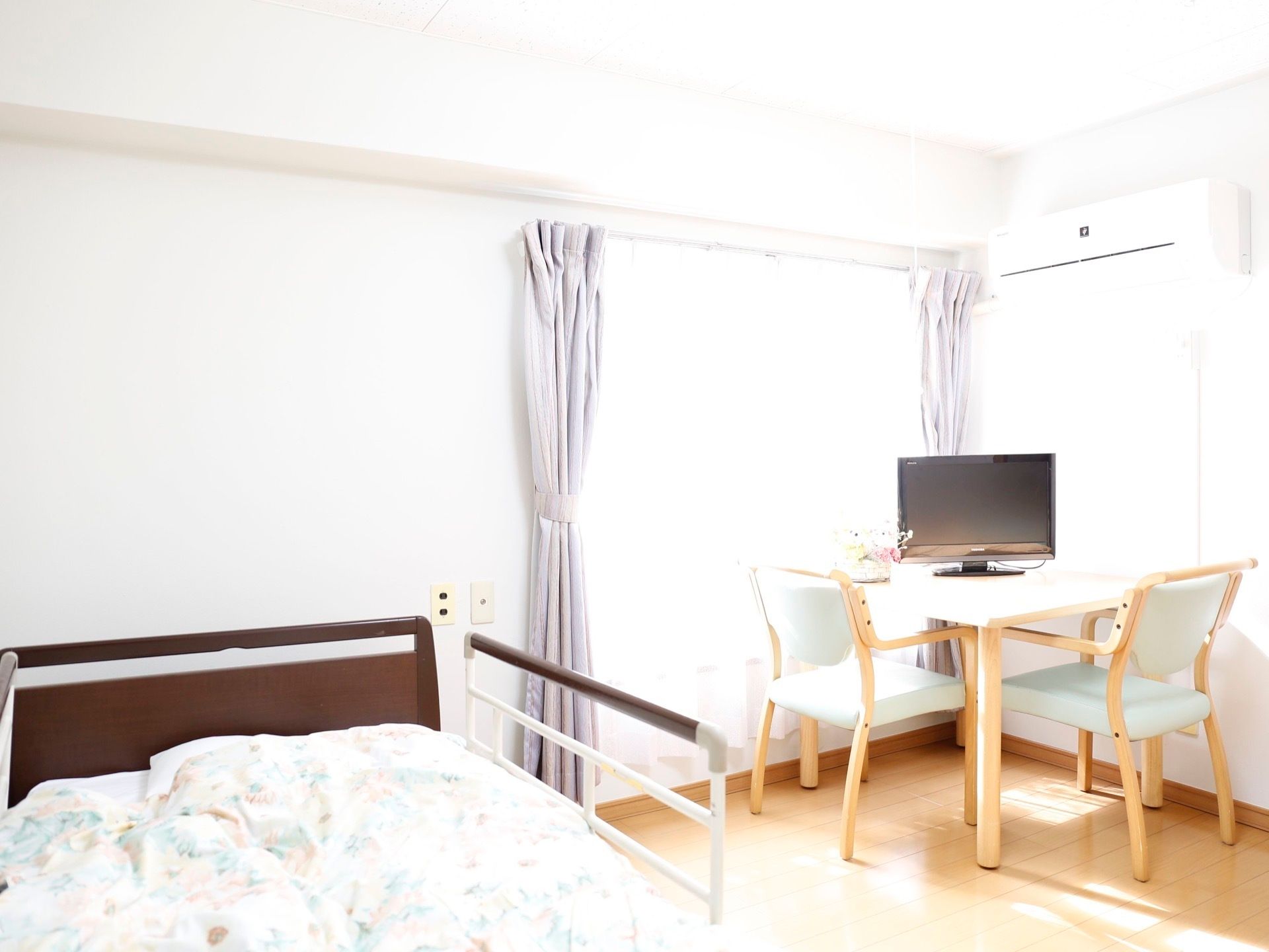白を基調にした明るく爽やかなデザインの居室である。窓際に２脚の椅子とテーブルが置いてあり、その上にテレビがある。