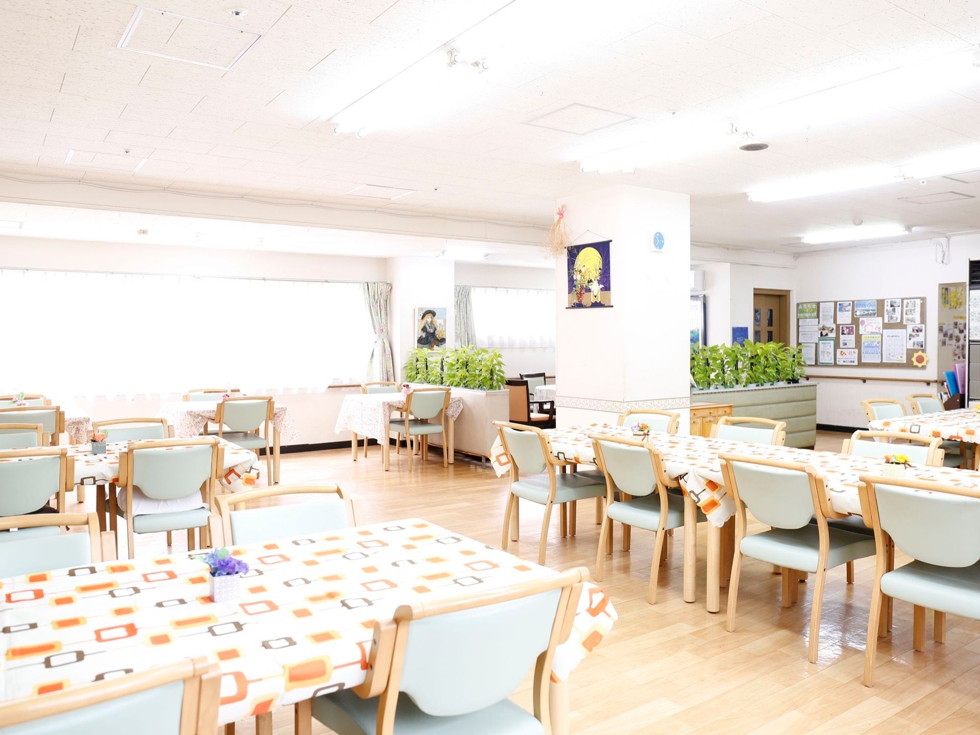 広々とした食堂には、数多くのテーブルと椅子が並んでいる。奥には横長の大きな窓があり、明るい光が差し込んでいる。
