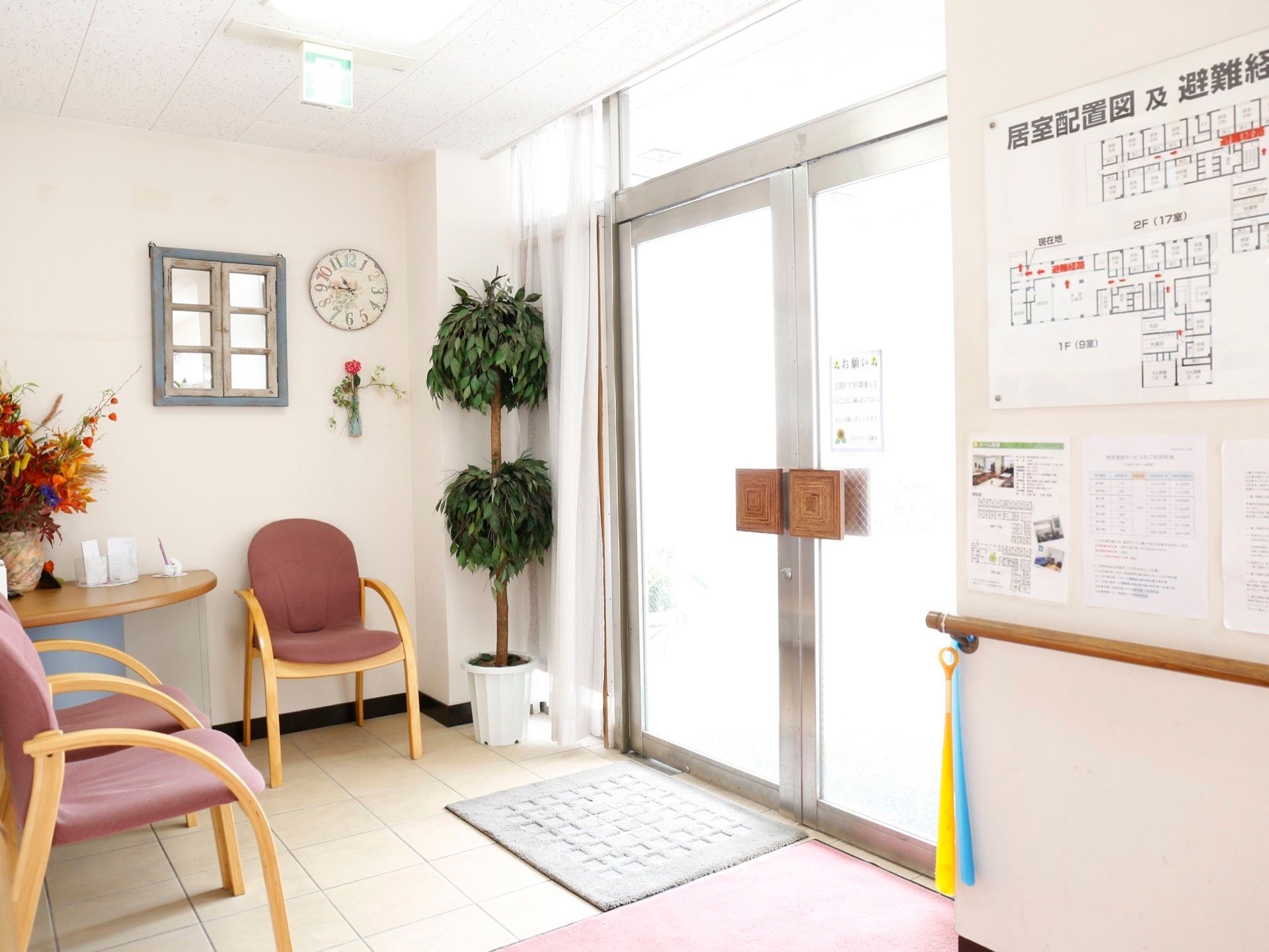 ドアの右横の壁には、居室配置図及避難経路が書かれたパネルが設置されている。左端には、大きな観葉植物が飾ってある。