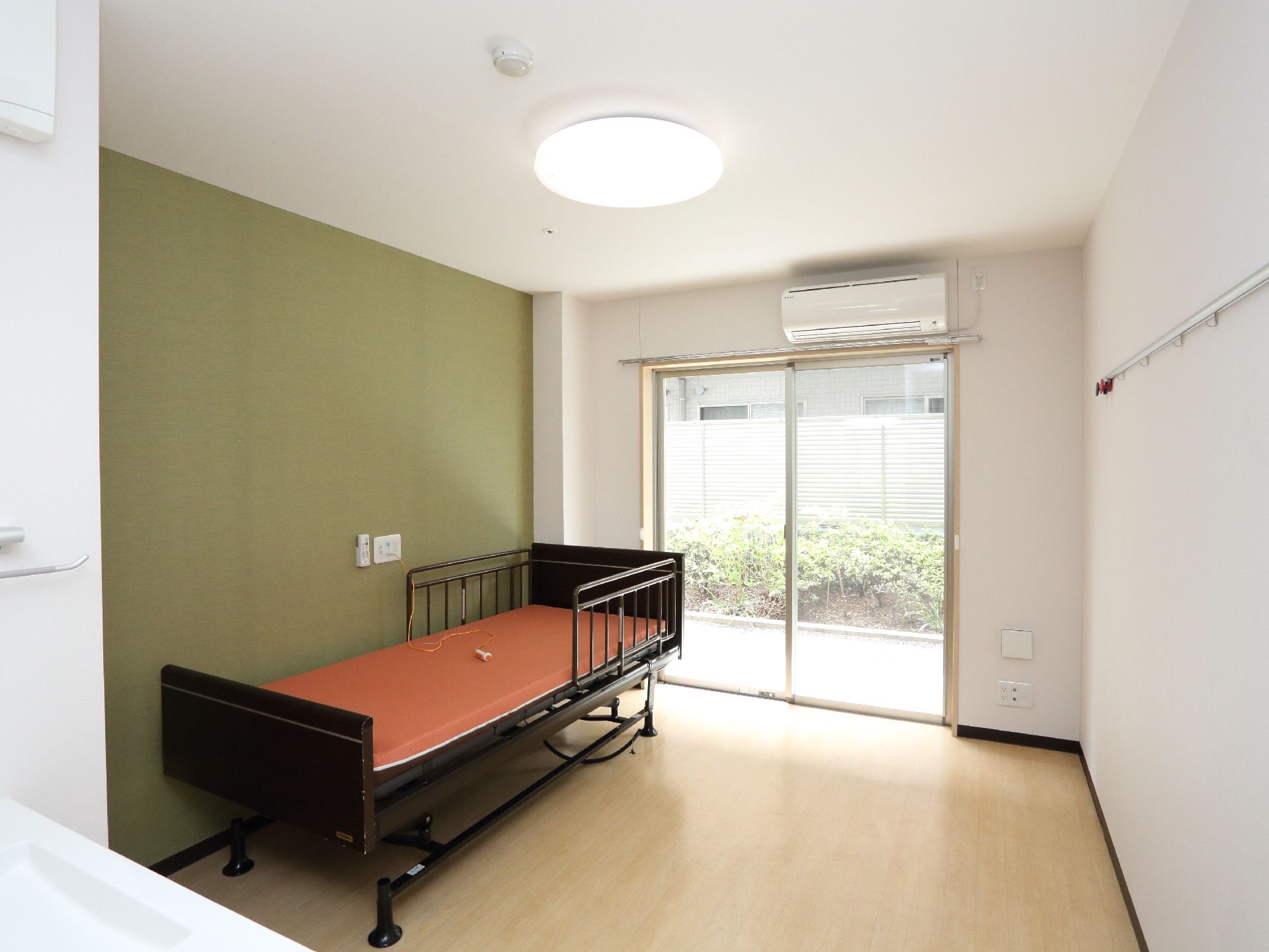 居室は大きな窓があり、自然の光が部屋に入る。ベッド完備。フローリングで段差は一切ない。空調も完備している。