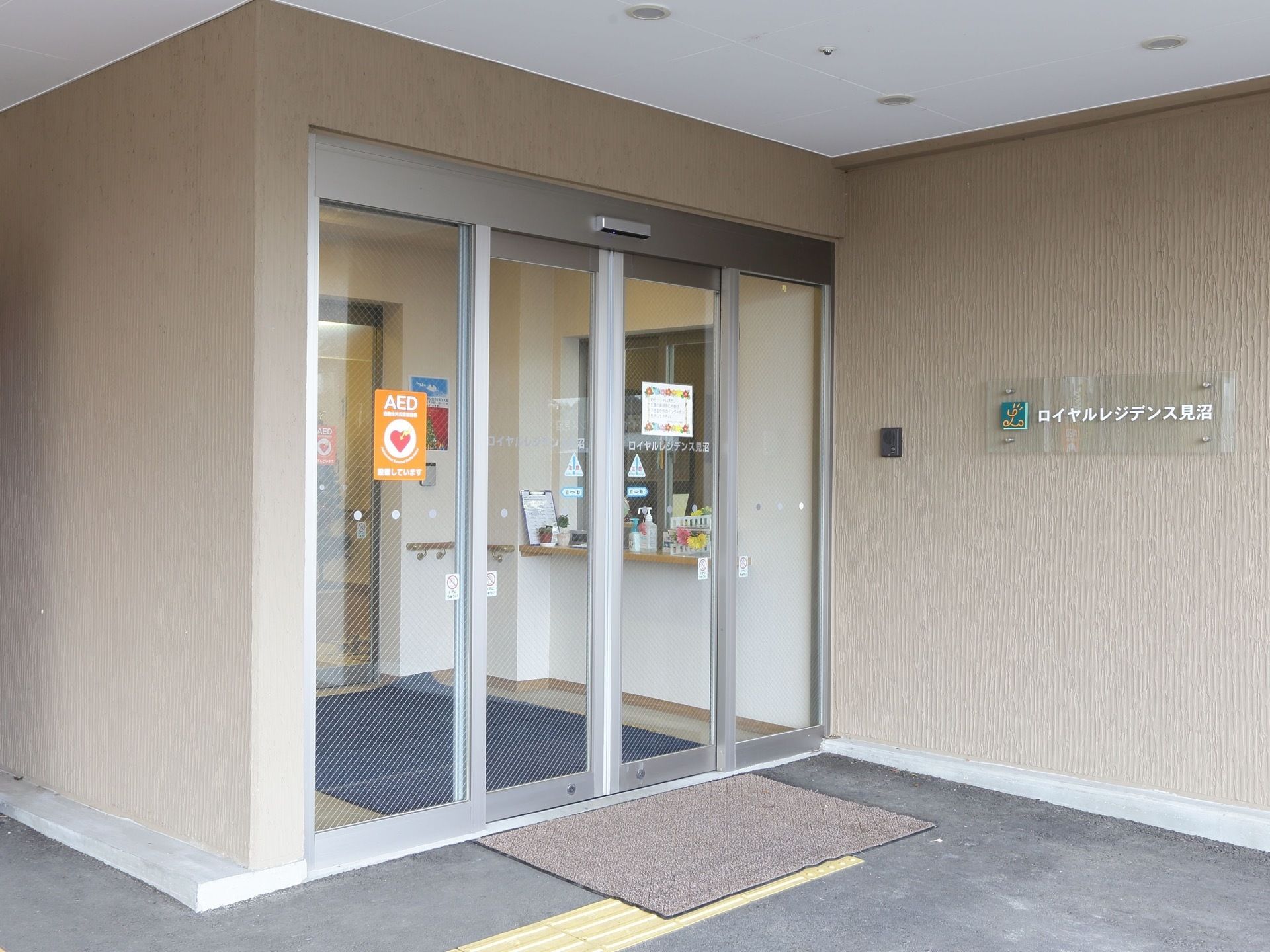 床には段差がない。点字ブロックが設置されている。自動ドアはガラス張りで開放感がある。AED設置の表示がある。