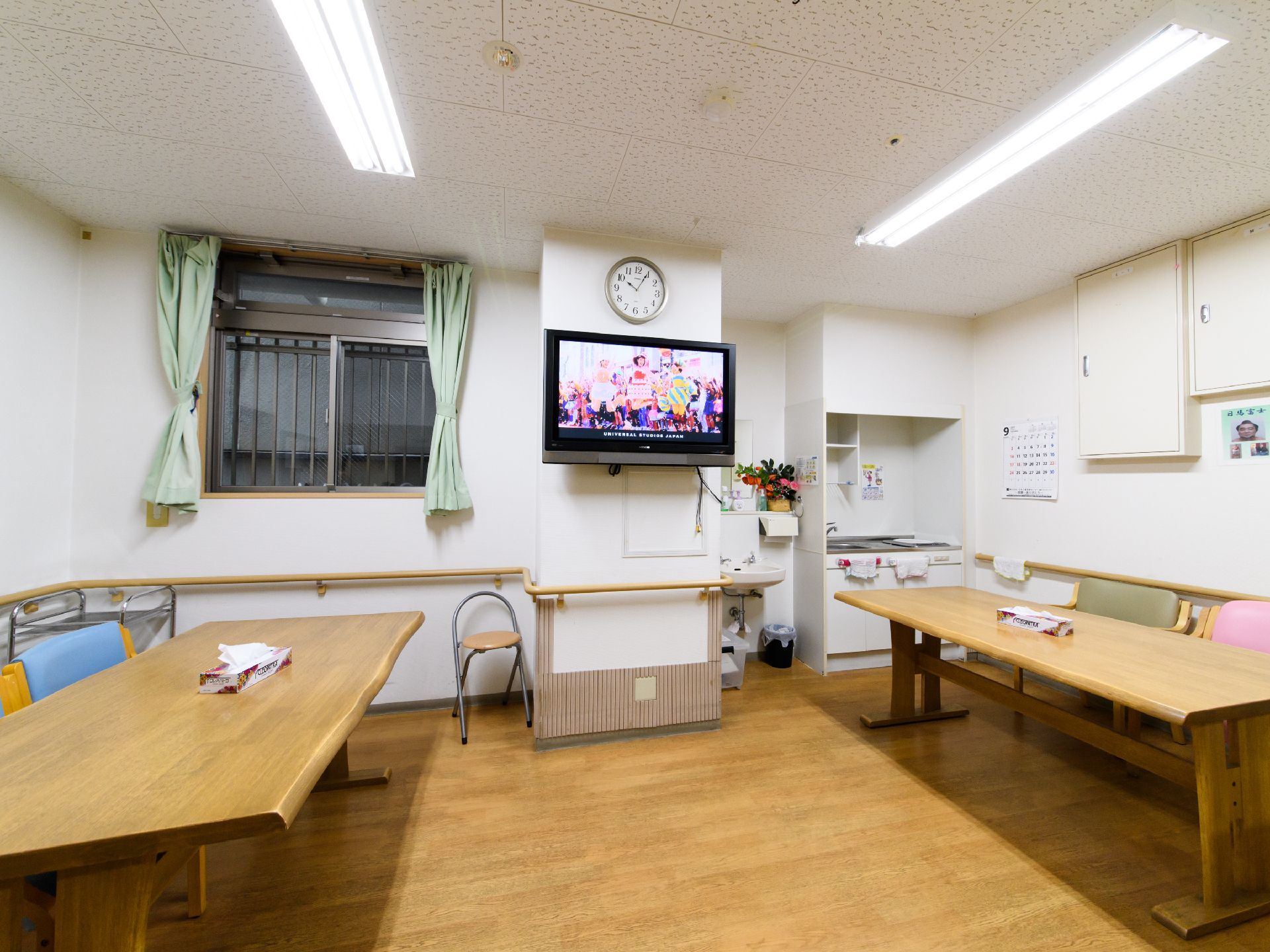 ダイニングの一角に、収納棚が付いた流し台があり、タオルがかけられている。その隣に洗面台があり、花が飾られている。