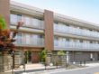 ３階建ての施設の建物の外観である。居室には施設の前を通る道路を望むことができるベランダが設けられている。