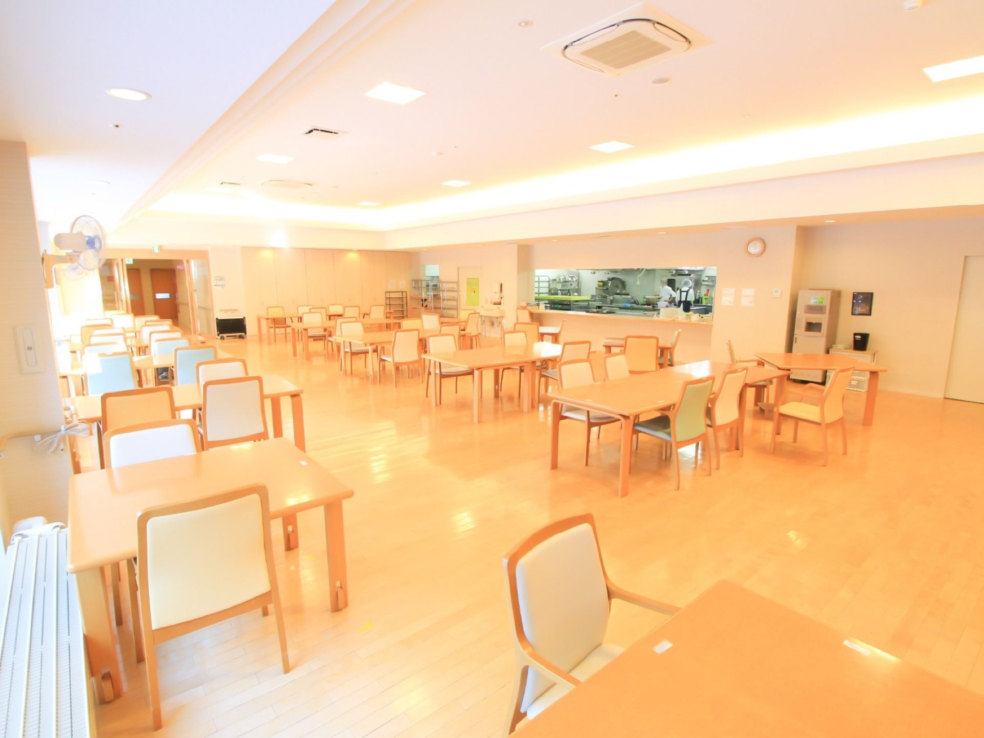 厨房が併設されている開放的な食堂。フロア内には、複数のダイニングテーブルや椅子がセッティングされている。