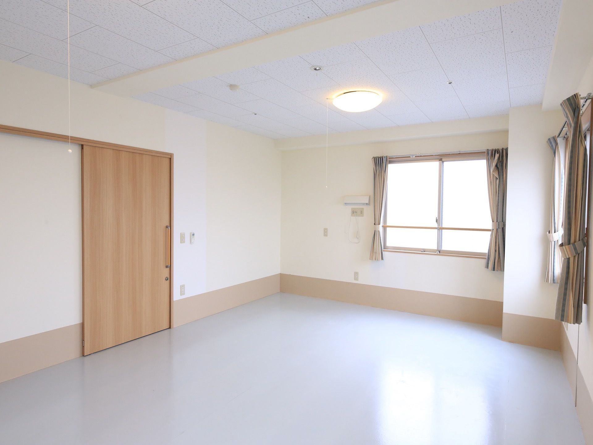 白を基調とした、日当たりの良い個室になっている。窓にはカーテンが掛けられている。扉はスライド式になっている。