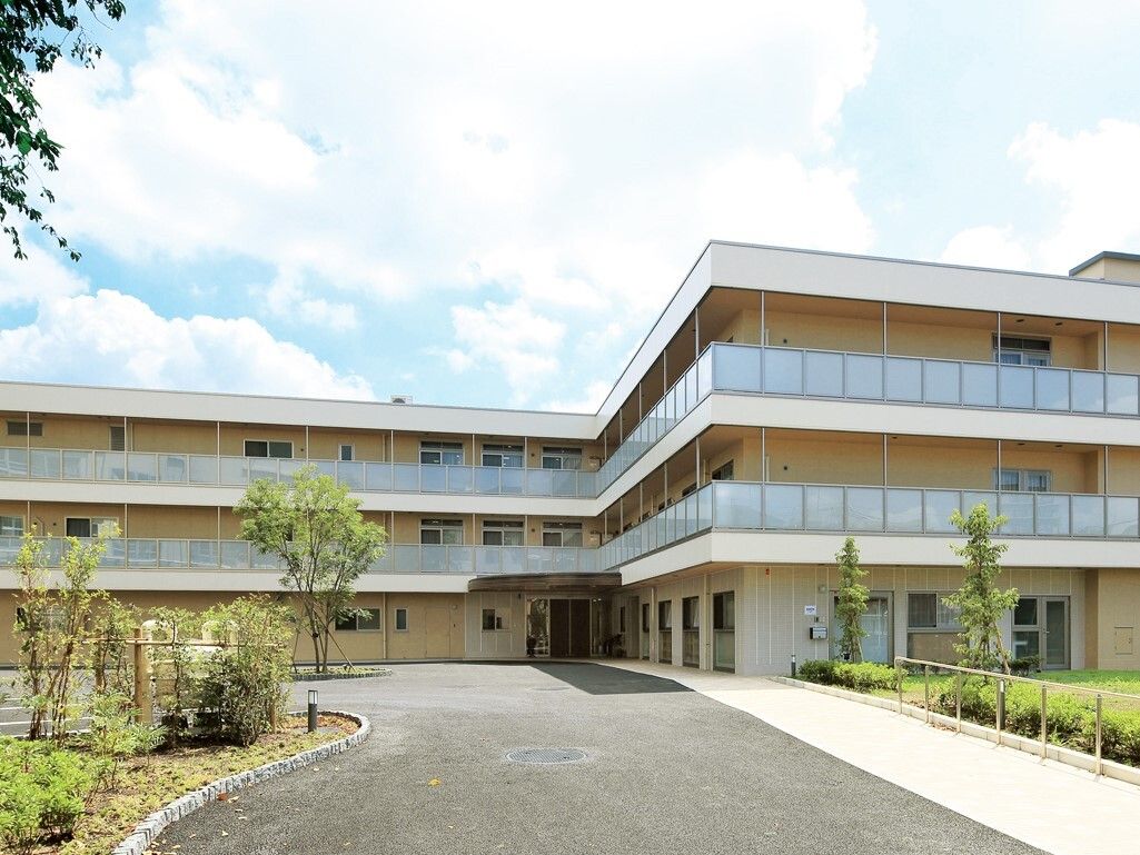 正面奥に3階建ての施設があり、手前に道路が伸びている外観