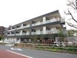 3階建ての建物は黒が基調となっていて鉄骨造になっている。各部屋のベランダ側が道路に面していて、エアコンの室外機が見えている。