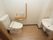 居室のトイレは、便座の脇にトイレットペーパーホルダーが2つありその上には小棚がある。そして小棚の上から直角方向に手摺りが設置されている。
