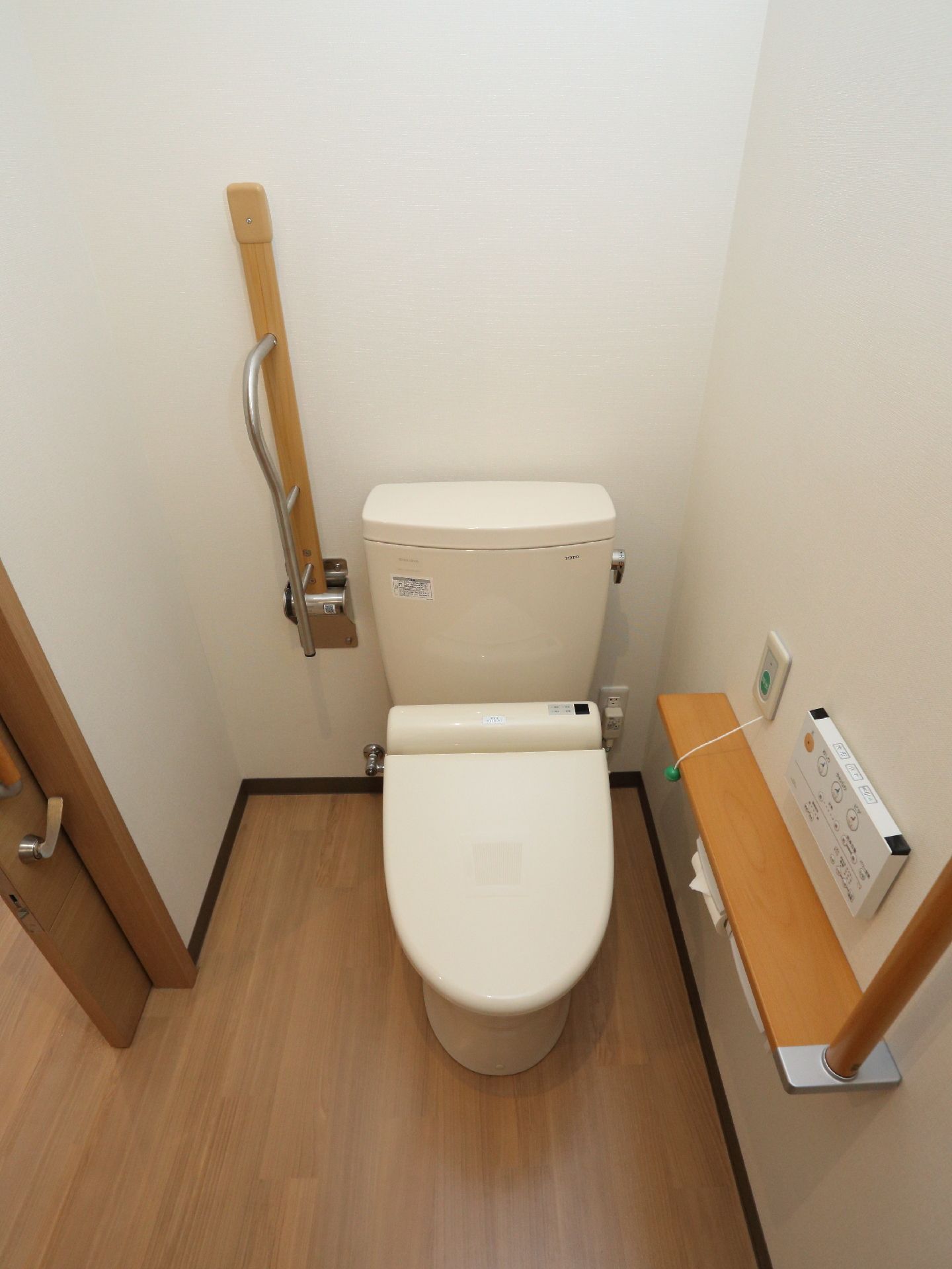 居室内のトイレは、便座の脇に握りやすい手摺りが付いている。また、壁には座位の状態で手が届く位置にナースコールが備え付けられている。
