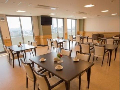食堂には窓が設置されており、壁には手すり、壁掛けテレビがある。茶色いテーブル、椅子もあり、テーブルにはティーカップが置かれている。