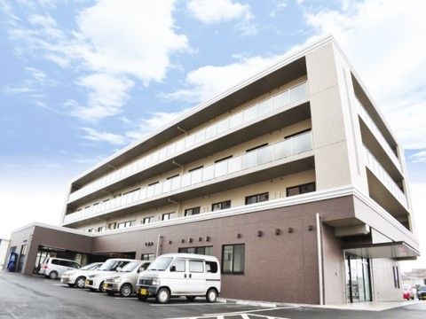 「はなことば 石巻」の外観。駐車スペースが広い、4階建ての居室のベランダ付きのホーム