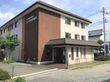 青空をバックに建っている３階建ての施設。植え込みや木などがいくつもあり、見ていると心が落ち着いてくる。