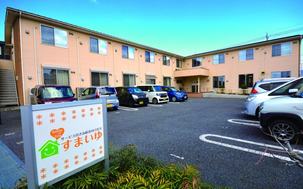 施設は２階建てで、ベージュを基調とした外観に外階段が取り付けられた外壁にブラウンのタイルを貼ったツートンカラーになっている。