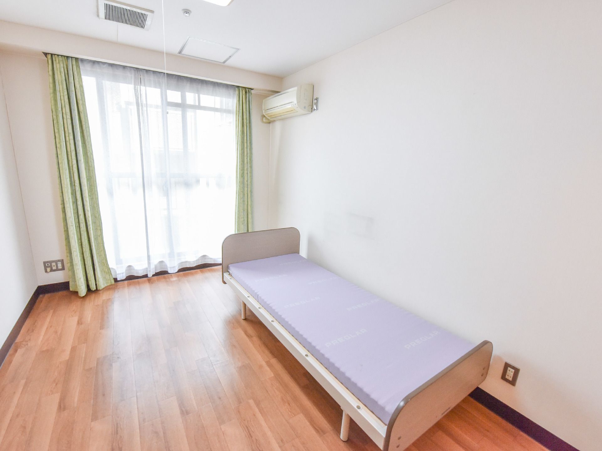 部屋にはグリーン系のカーテンがついた、窓がある。光が入るので、日中には明るくなる。コンセントプラグが4本分以上も取り付けることができる。