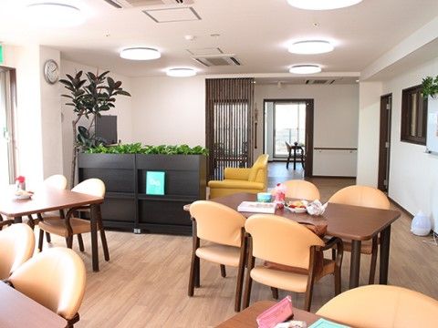 室内には４人用テーブルが適度な間隔で４卓置かれている。マガジンラック、テレビ、ソファもあり、木製家具は茶系で統一されている。
