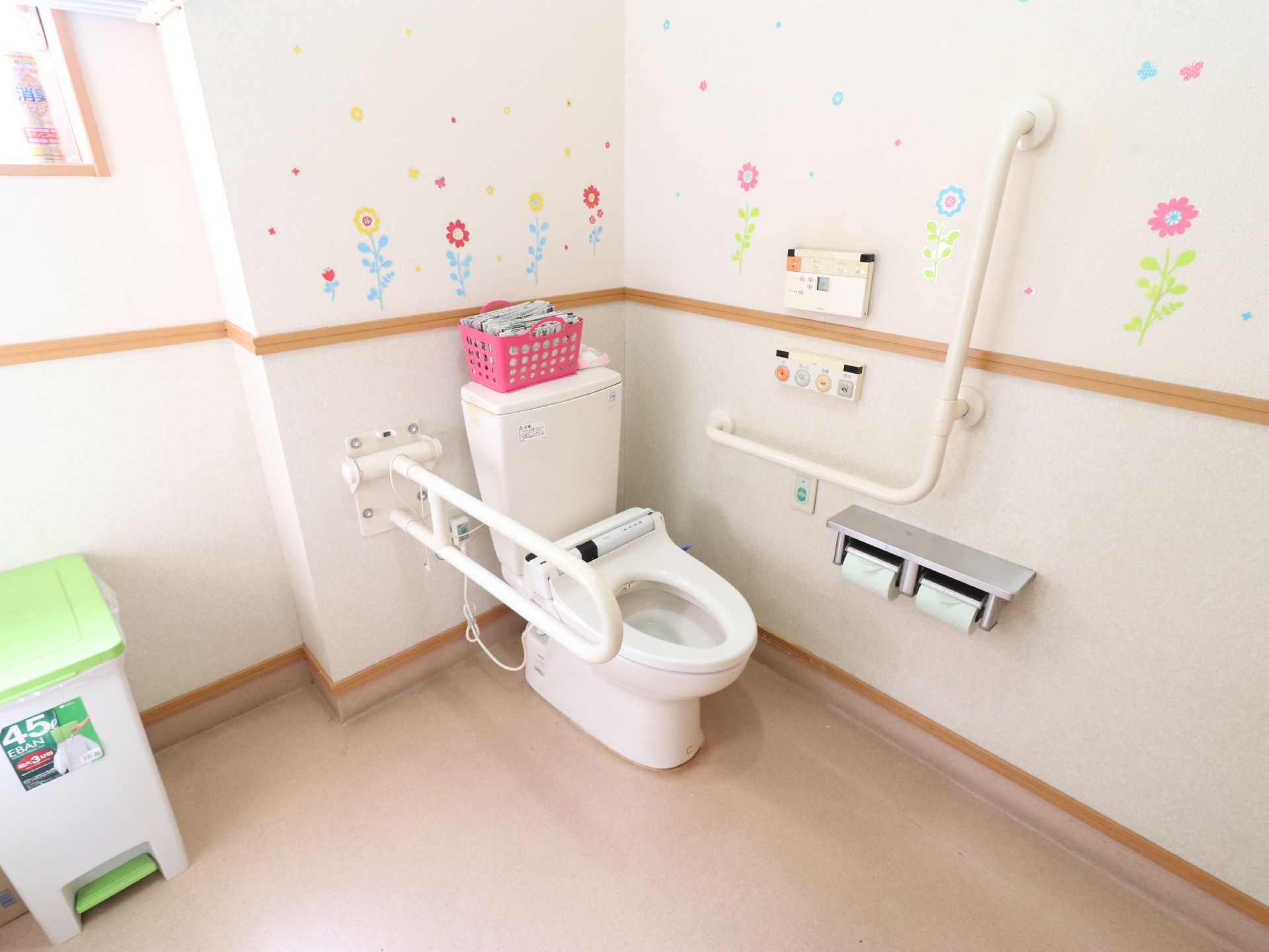 明るく清潔感のあるトイレである。便器の左側には可動式の手摺が設置してある。便座は温水洗浄便座になっている。