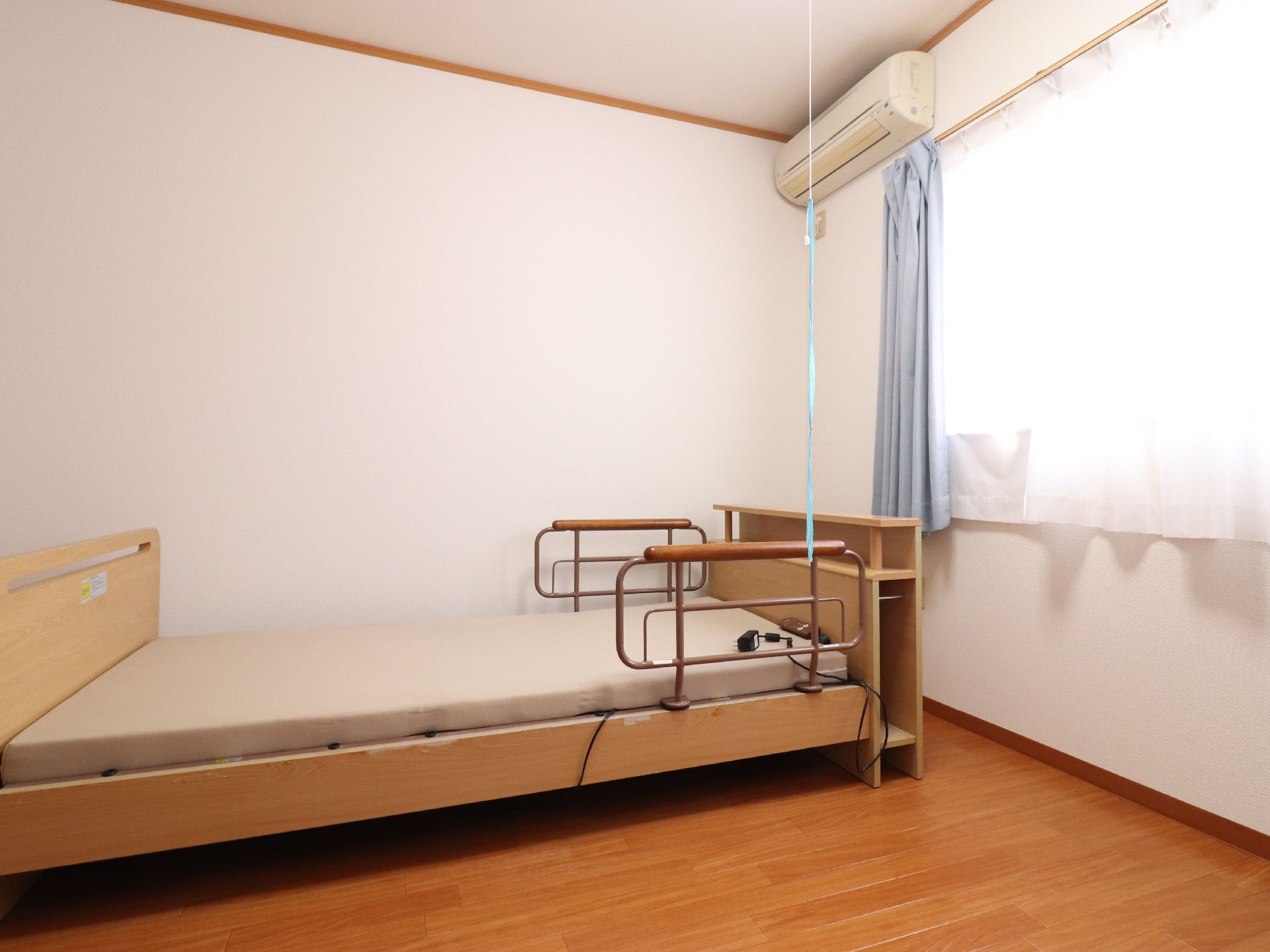 個室には転落防止の柵が備わっているベッドが置かれている。エアコンの設備も整っている。窓からは日差しが差し込んでいる。