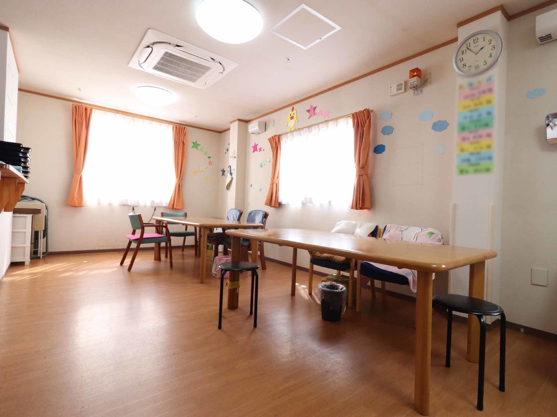 テーブルにはひじ掛け付きの椅子やパイプの丸椅子などが備えられている。壁には画用紙で作った工作が飾られている。
