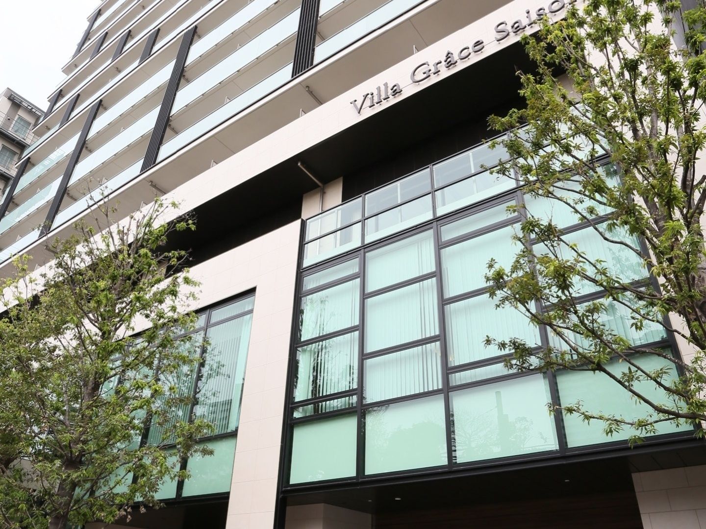 高級マンションのような建物で、２階の部分がガラス張りになっている。入口近くの白い柱に、施設名の書かれた茶色い看板が取りつけられている。