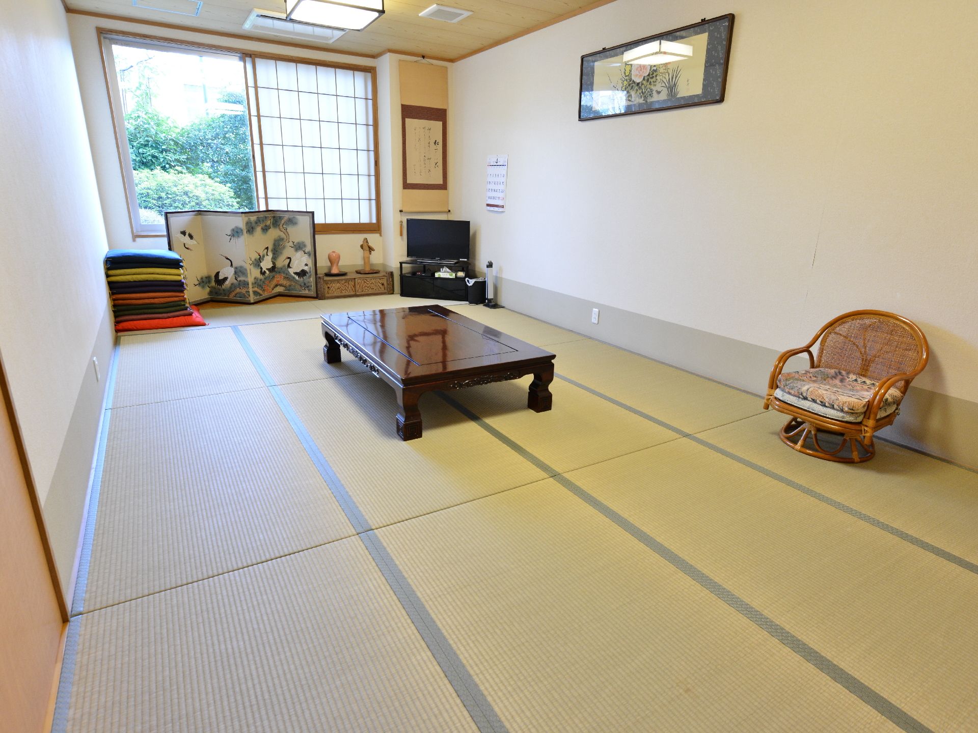 居室には畳敷きの和室が用意されている。窓には障子があり、壁には額と掛け軸が掛けられている。テレビが設置されている。