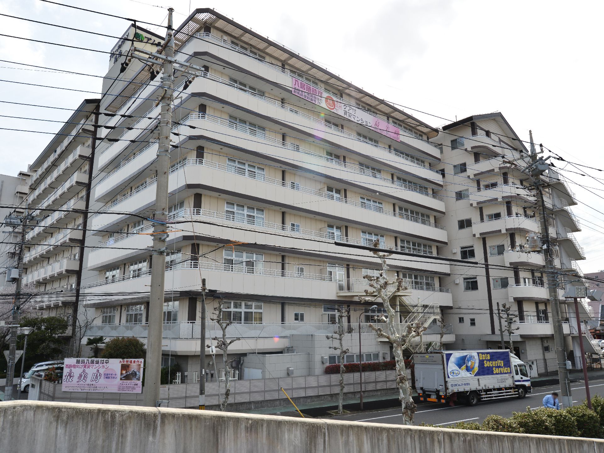 施設は白の8階建てのマンション風の外観の建物。建物の敷地も大きくとても多くの部屋数があるのが判る。壁面には施設名の看板が貼られている。