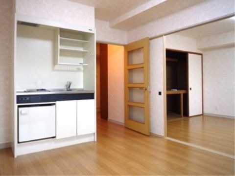 木目調のフローリングの２間続きの居室である。収納が充実したミニキッチンを設置し、隣の部屋には押入れを設けている。