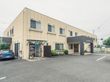 淡いベージュ調の施設外観である。外壁には施設名が記された看板が設置されている。敷地内には車が1台停まっている。