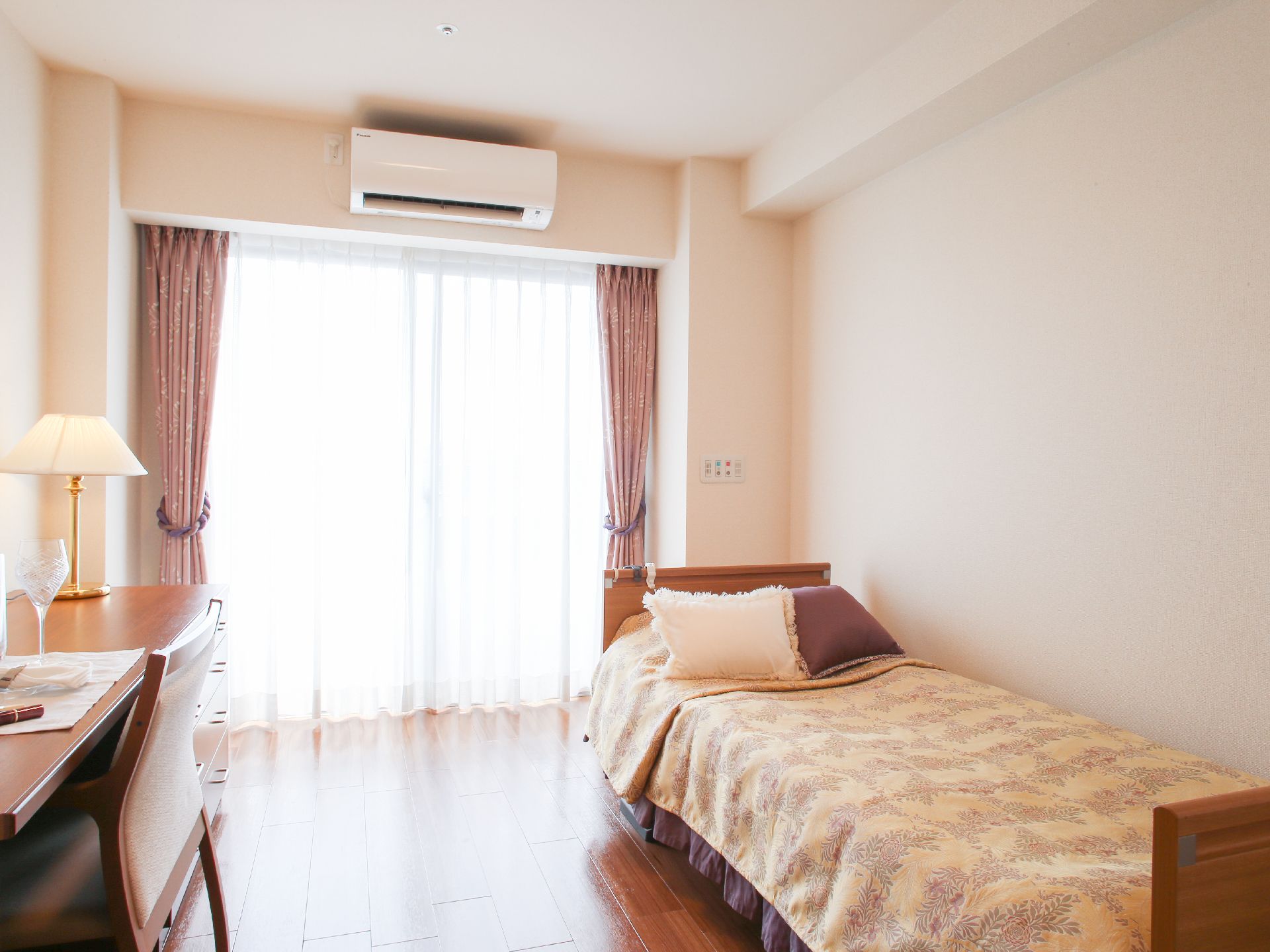 ワンルームの部屋にベッドや机などがコンパクトにまとめられており、介護用のベッドは高さが低いので、安心できる。
