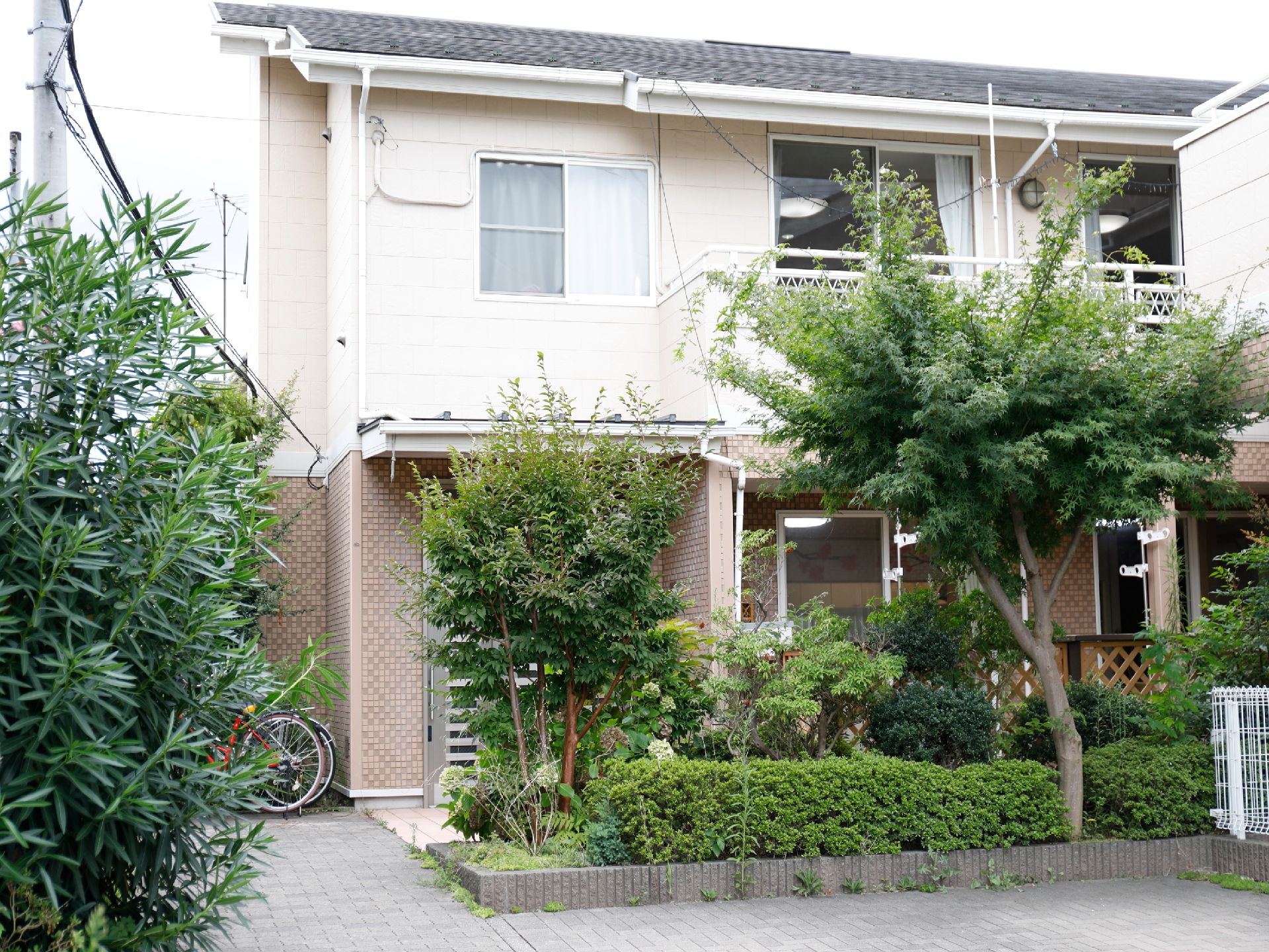 一般民家のような作りの木造モルタルの建物。立木が何本かあって、ラティスで囲まれているので目隠しになっている。