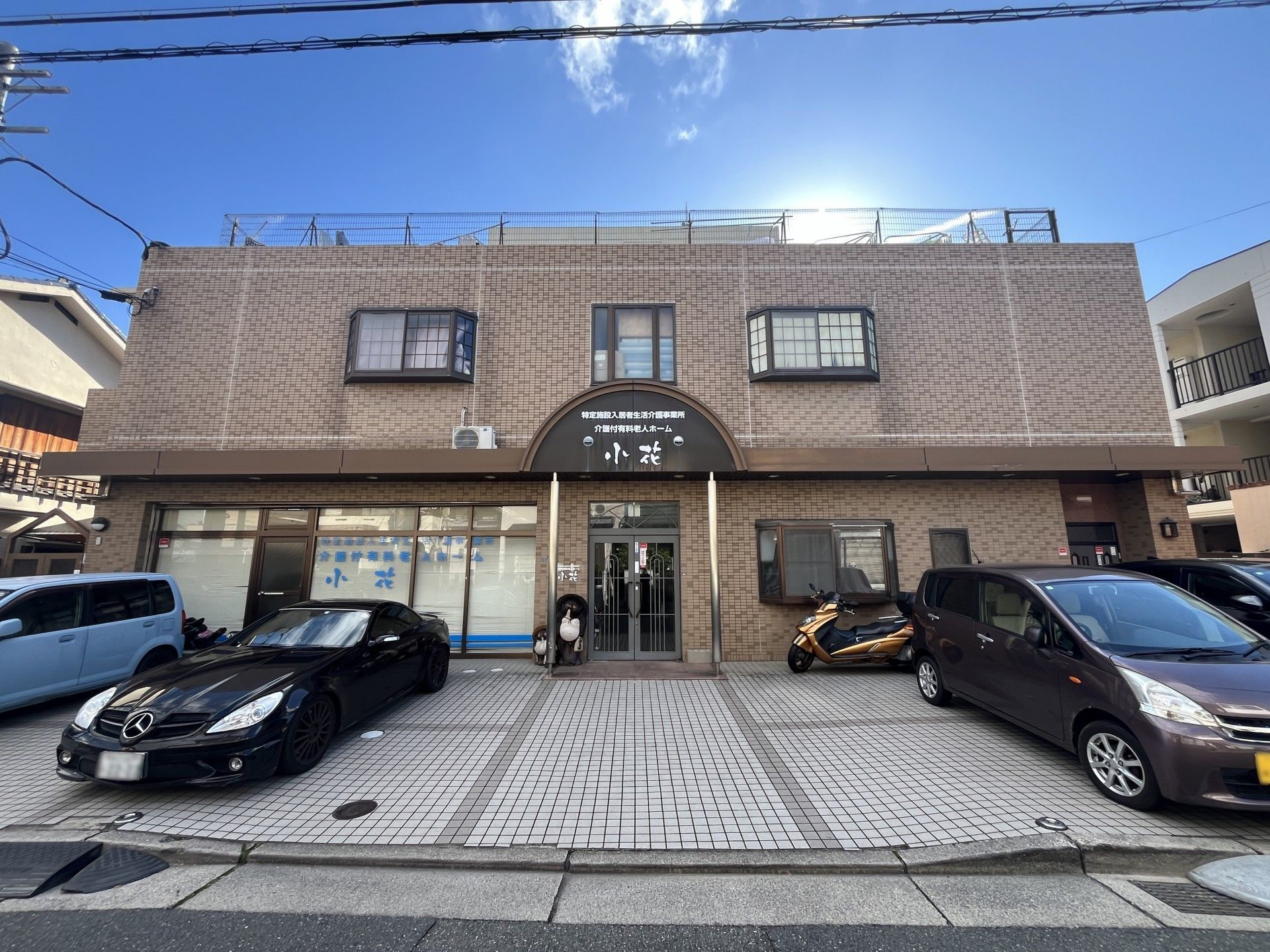 建物前に駐車スペースを備えた、２階建てのブラウン色の施設外観