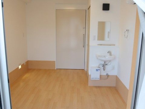 居室の窓は大きく日差しが室内に入る。洗面台と鏡が設置され、壁にはタオル掛けがつけられている。床はバリアフリー。