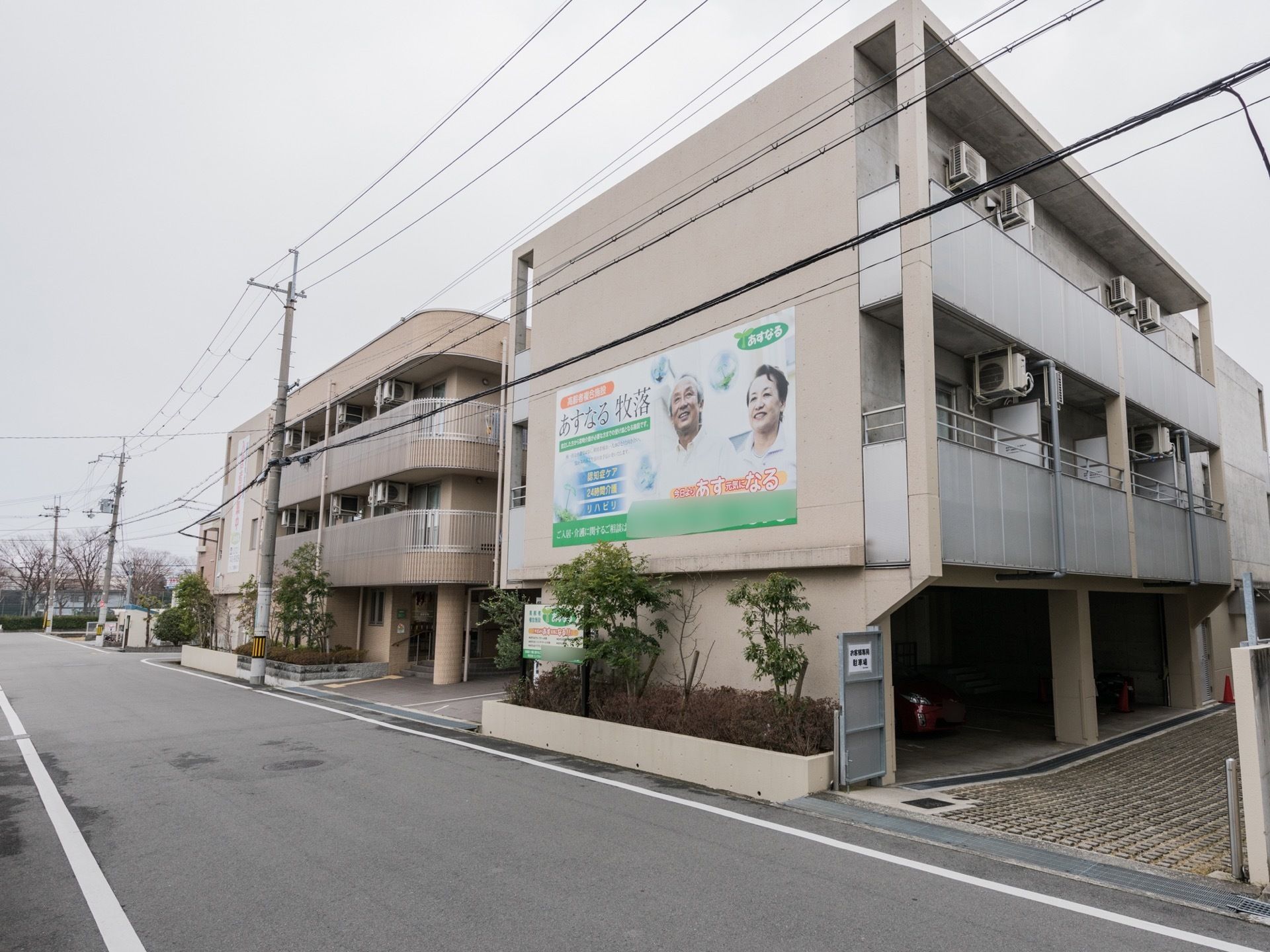 3階建ての建物で、1階部分に駐車場がある。各部屋にベランダがある。周囲に木が植えられている。アイボリー色の外壁である。