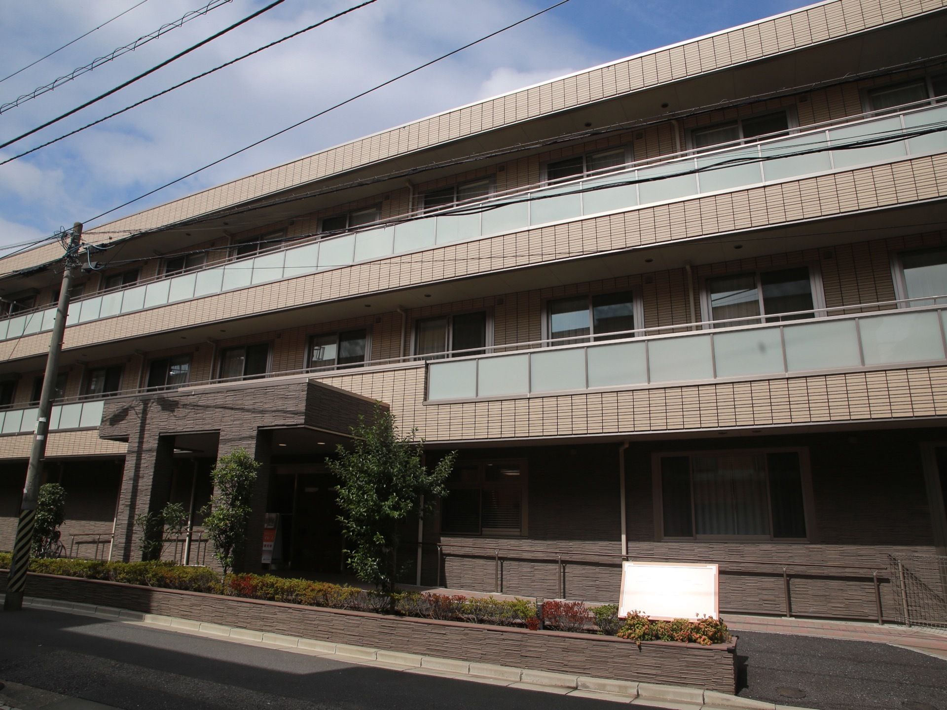 重厚な雰囲気の建物。２階と３階はベランダになっており、通りから見えにくい材質のパネルが用いられている。