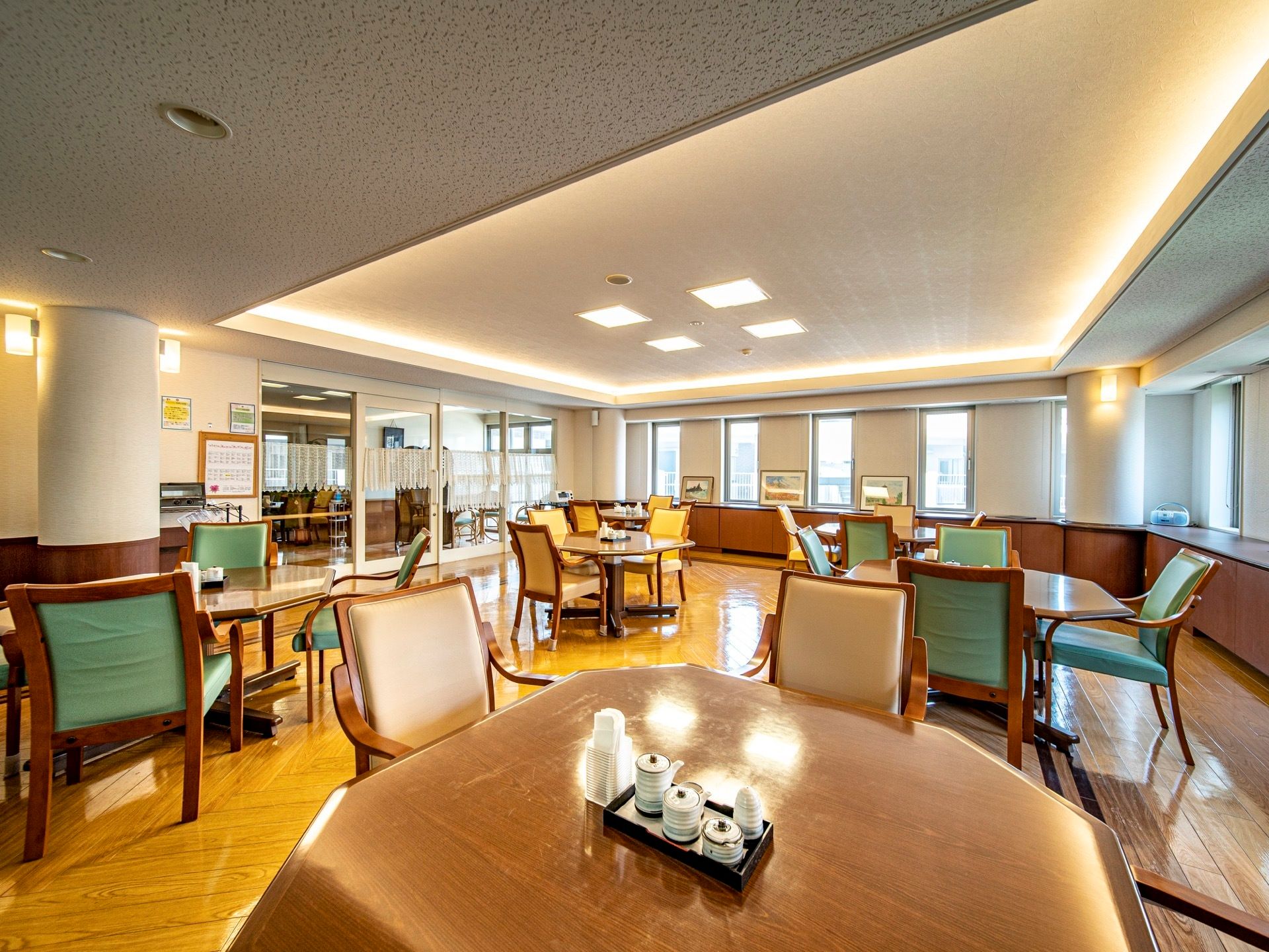 食堂は間接照明で部屋全体が明るく、落ち着いた雰囲気になっている。日中は小窓から日が注ぎ込んでいる。テーブルセットがいくつかある。