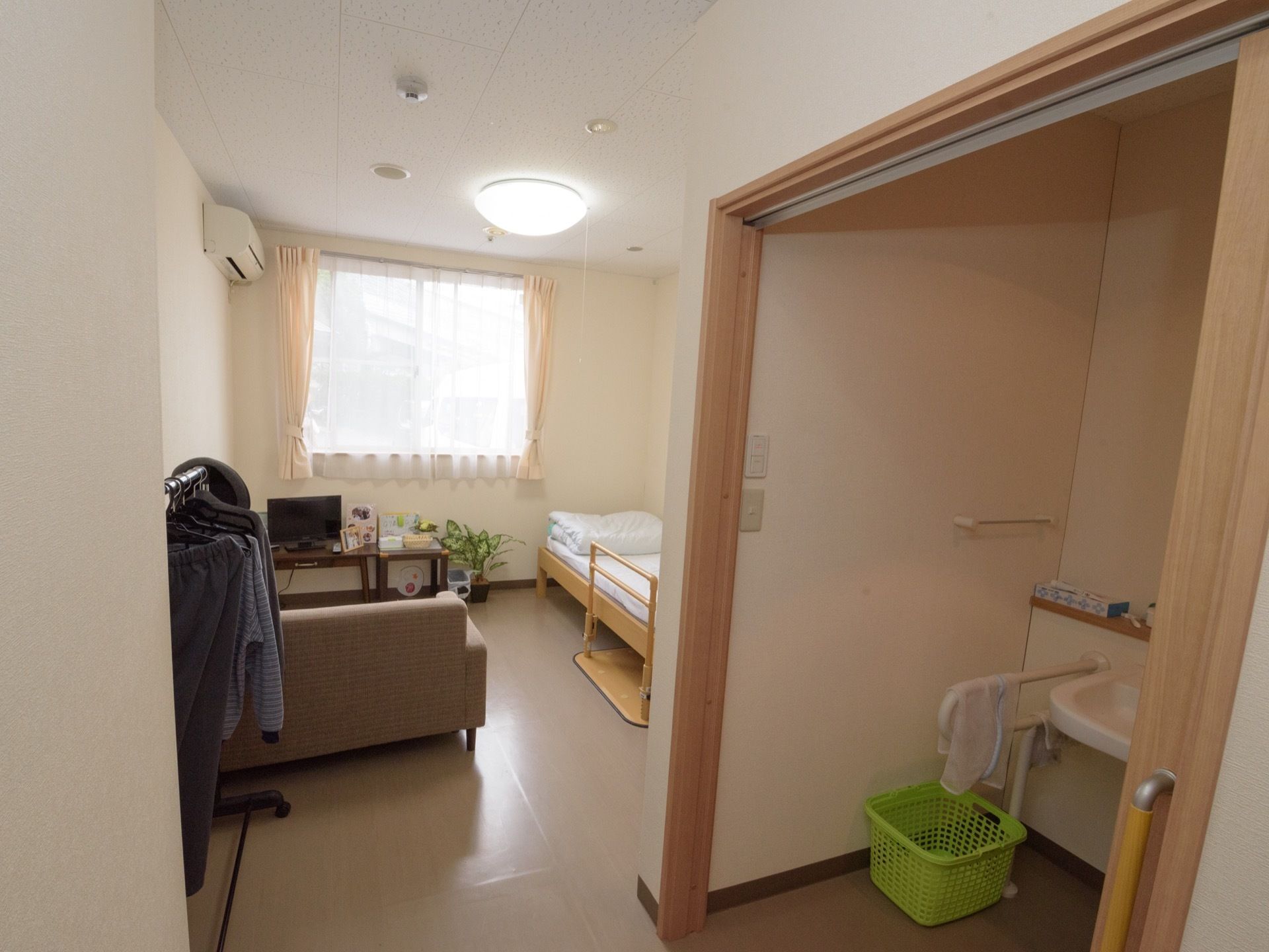 居室の床は扉部分も段差なく整えている。室内にはベッドとソファーがあり、テーブルの上にテレビを設置している。