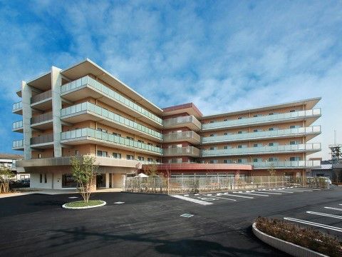 ２階以上の階にベランダが設置された、大きなＬ字型の５階建ての建物。建物前には広い駐車場が完備されている。
