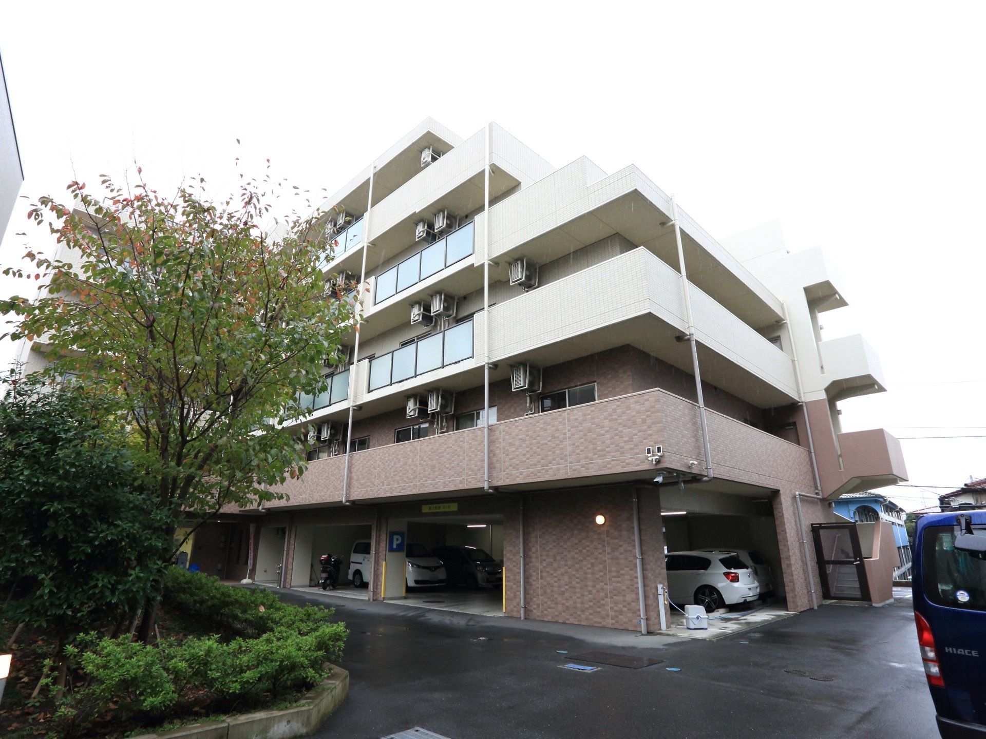 5階建て施設は1階に駐車スペースのあるマンションのような外観である。木や草花も植えられている穏やかな環境となっている。