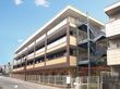 ４階建てで外階段が付いており、マンションのような建物である。まわりには白いフェンスが立てられている。