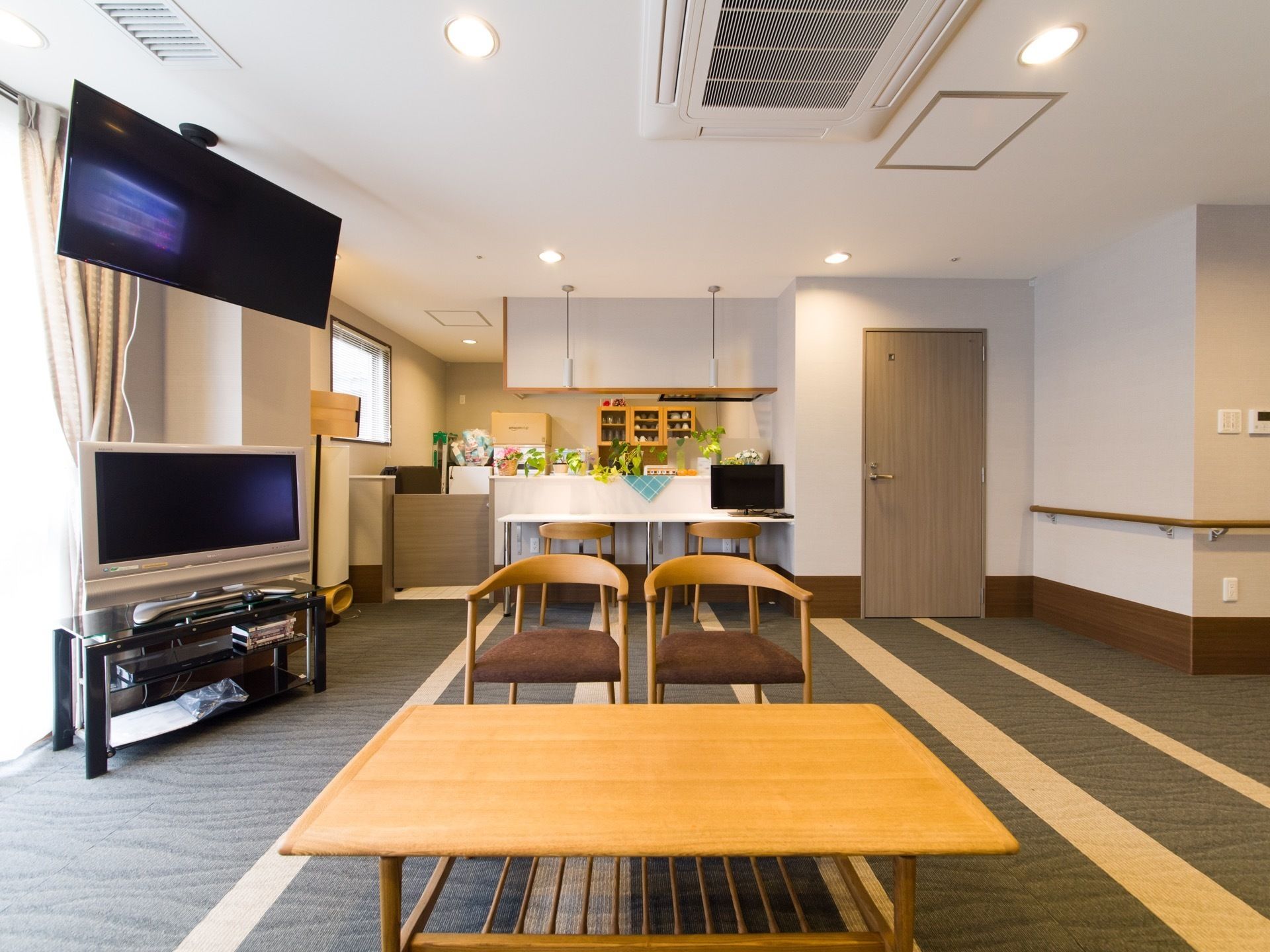 木製のテーブルと椅子がある。カウンターキッチンになっており、テーブルの上には小さなテレビを置いている。