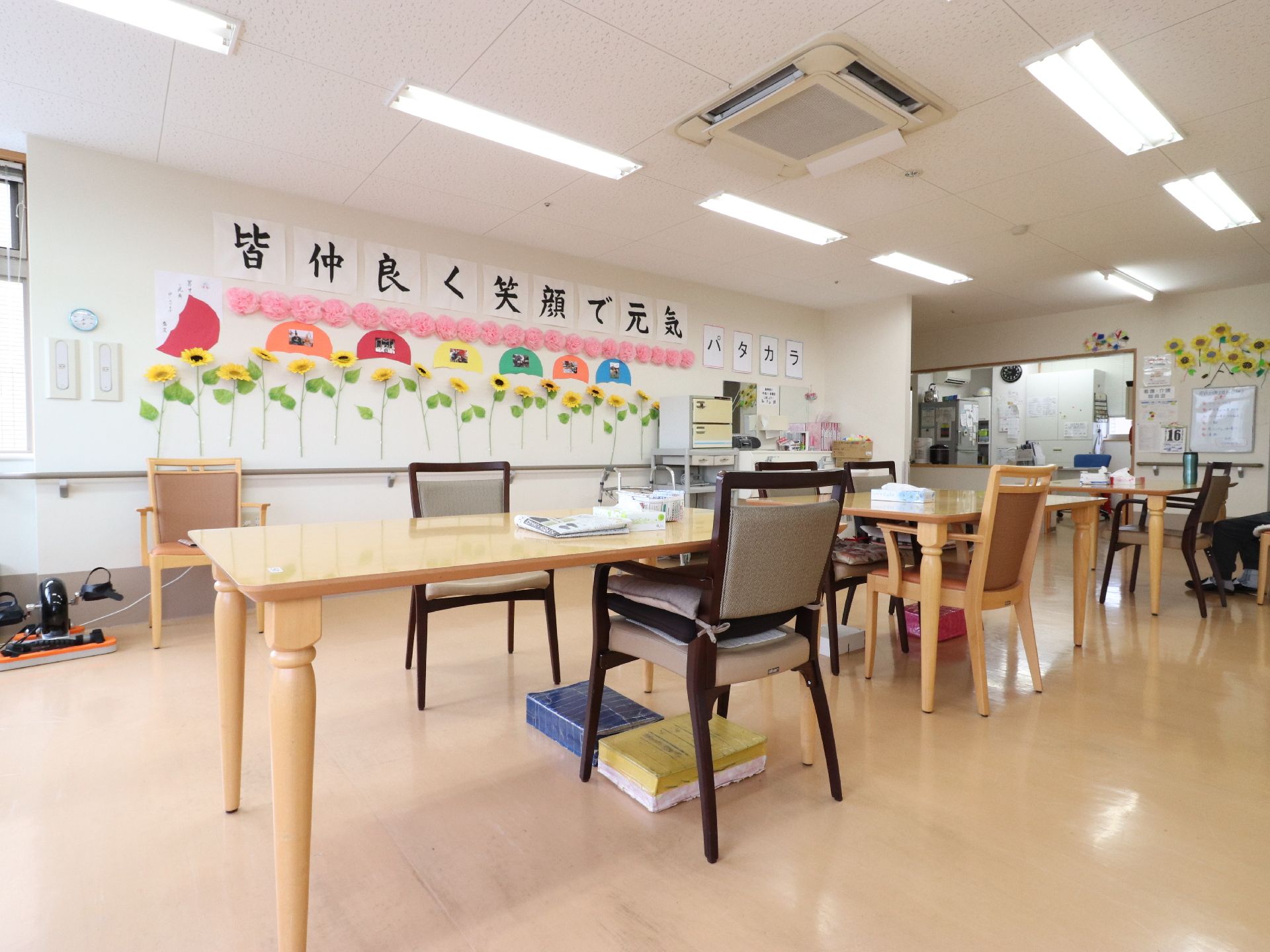 テーブルの下には、入居者が座った際に足が届くように台が設置されている。向かって右奥には厨房が併設されている。