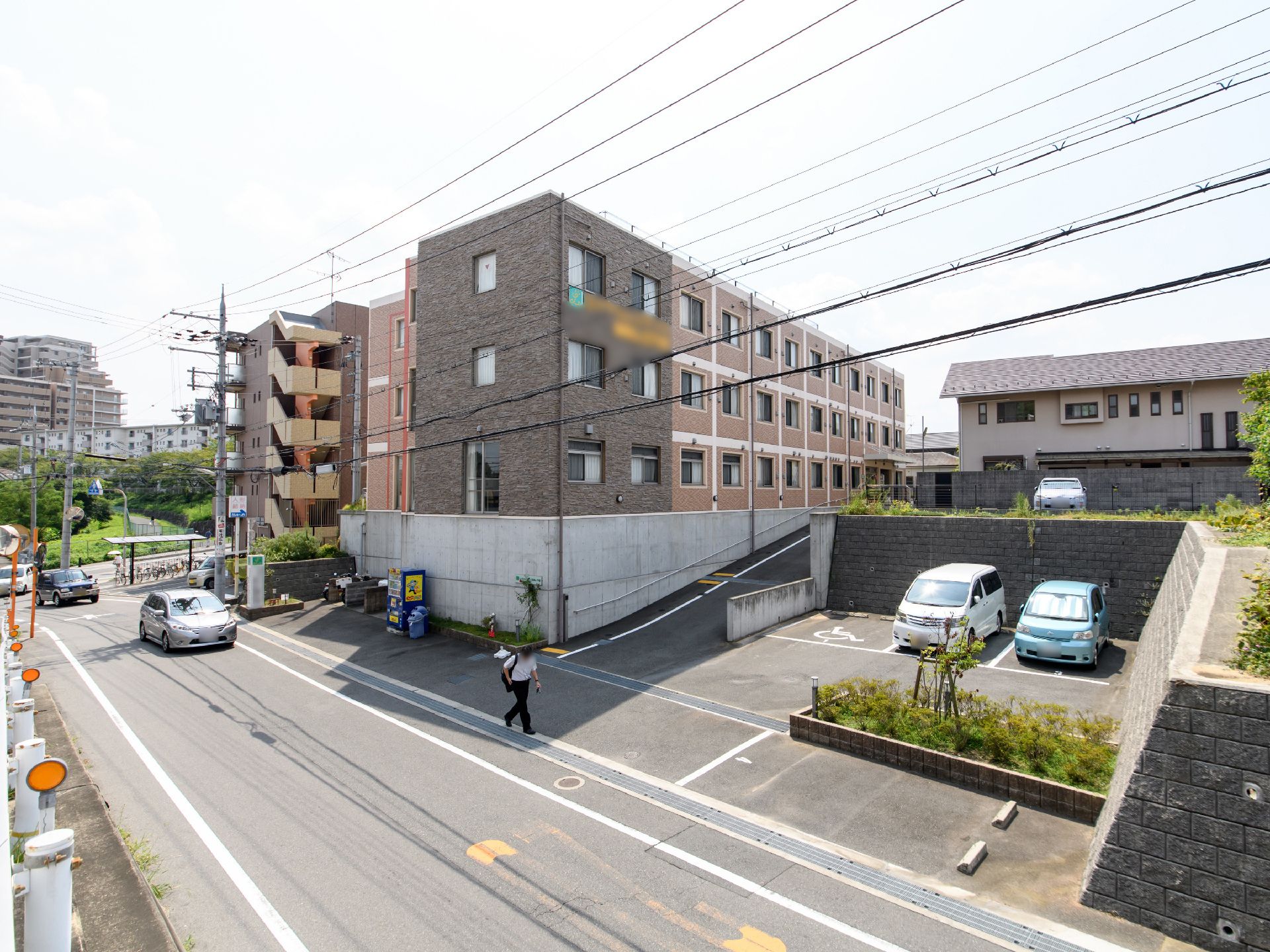 隣接している道路の横に4台分の駐車所がある。車椅子専用の駐車スペースが用意されている。建物は道路より高いところに建っている。