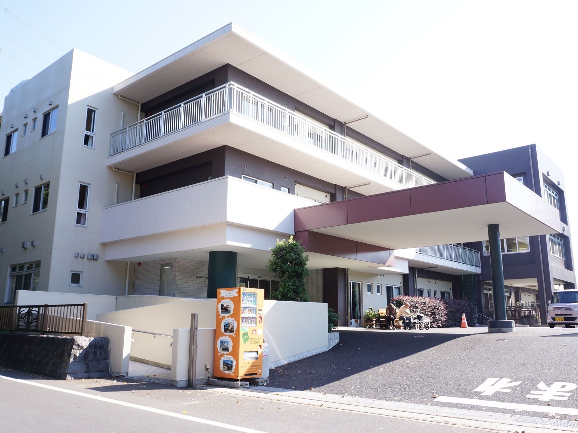 施設建物の外観。正面ゲートの左側には車椅子用のスロープと、ジュースを販売する自動販売機が設置されている。