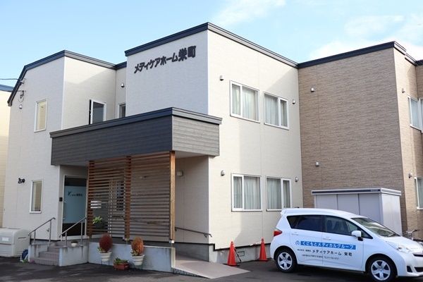 ２階建てのグループホームである。玄関前には、手すりが付いた階段や傾斜の緩やかなスロープが設置されている。