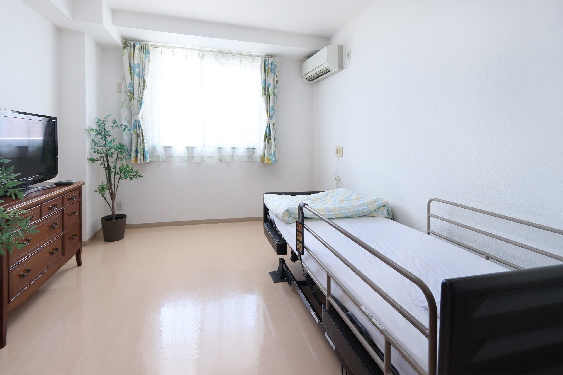 白とベージュを基調とした居室の窓にはピンクのカーテンが取り付けられ、明るい雰囲気になっている。居住性にも満足できる広さがある。