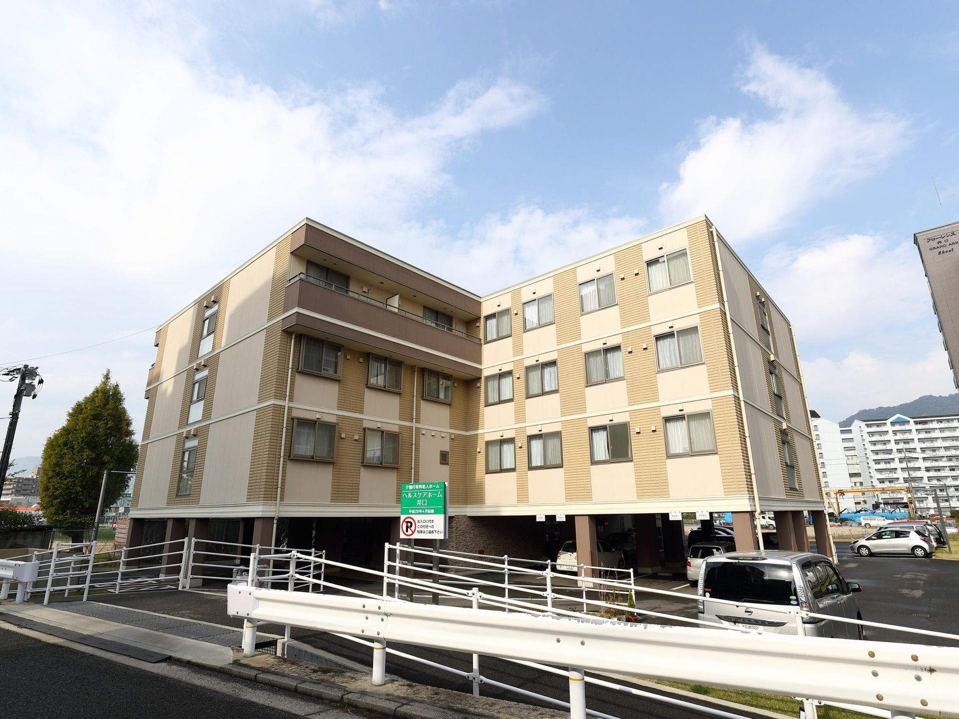 施設の建物は4階建てでL字型である。1階部分には駐車スペースがある。外壁はベージュ色である。施設名が記された看板が立てられている。