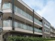 ブラウンとベージュの外壁で、ベランダがついたマンションタイプの建物である。施設の周りには植木が植えられている。