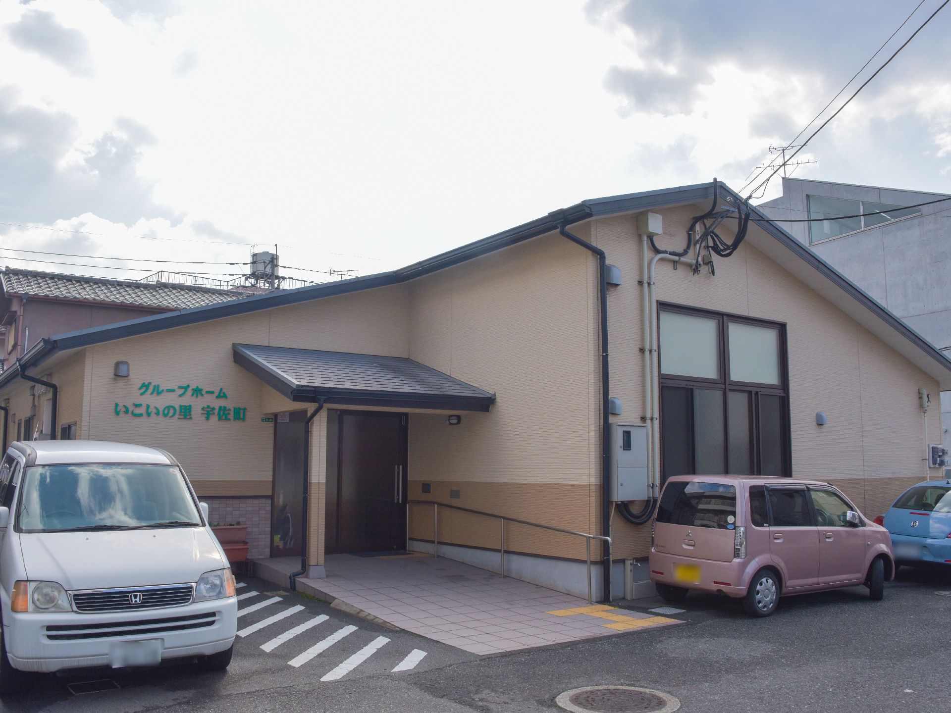 エントランスまでのアプローチには手すりがある。スロープになっている。車を停めるスペースがある。ドアはスライド式。